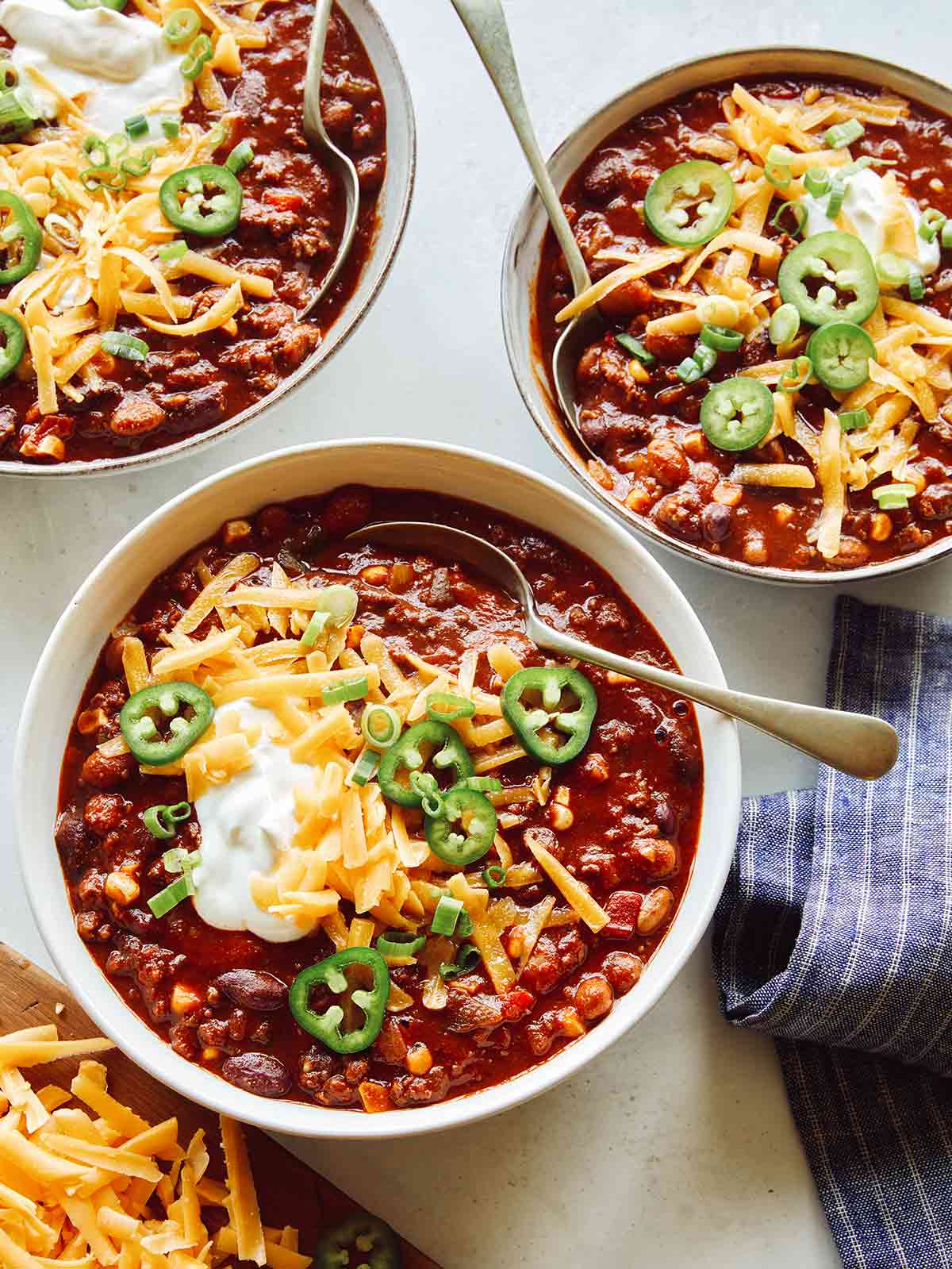 Kitchen sink chili in three bowls with toppings. 