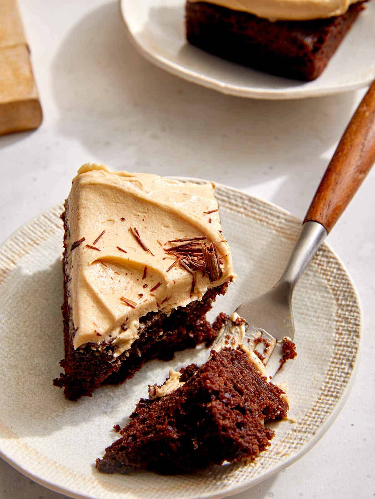 A slice of chocolate sheet cake with peanut butter frosting and a bite taken out. 