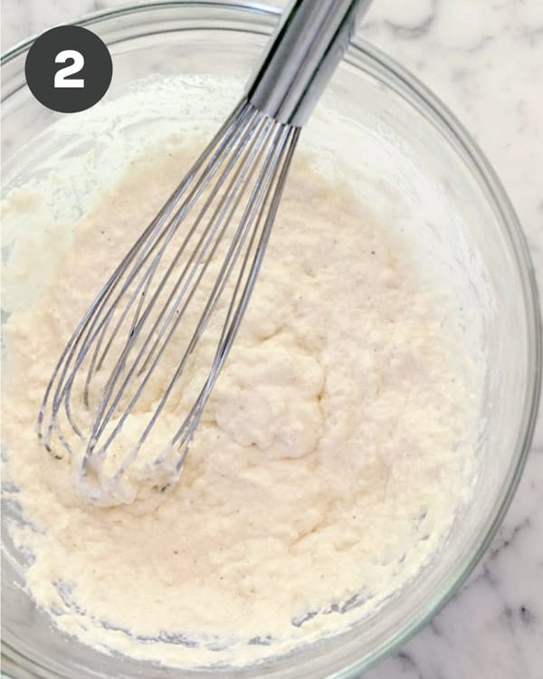 A bowl of the dry ingredients mixed with seltzer water with a whisk in the bowl. 