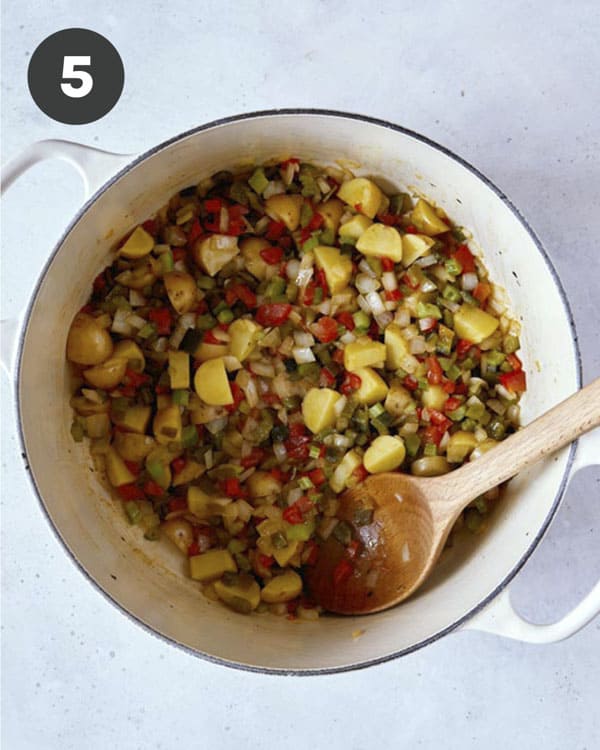 Vegetables cooking in a stock pot to make corn chowder.