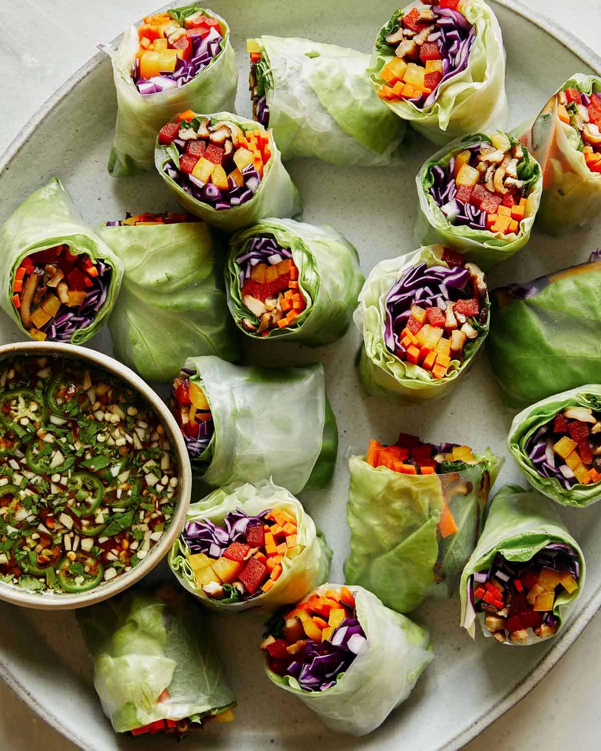 A platter of fresh spring rolls with a dipping sauce.