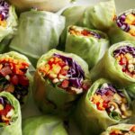 A platter of fresh spring rolls with a dipping sauce.