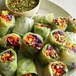 A platter of fresh spring rolls with a dipping sauce.