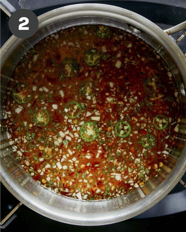 Dipping sauce ingredients in a pot with fresh herbs.