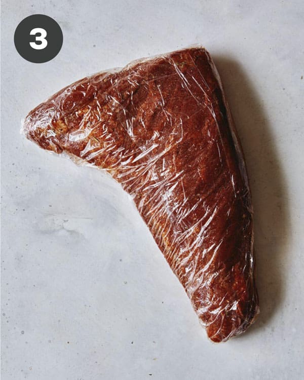 Tri tip with rub wrapped in plastic wrap.