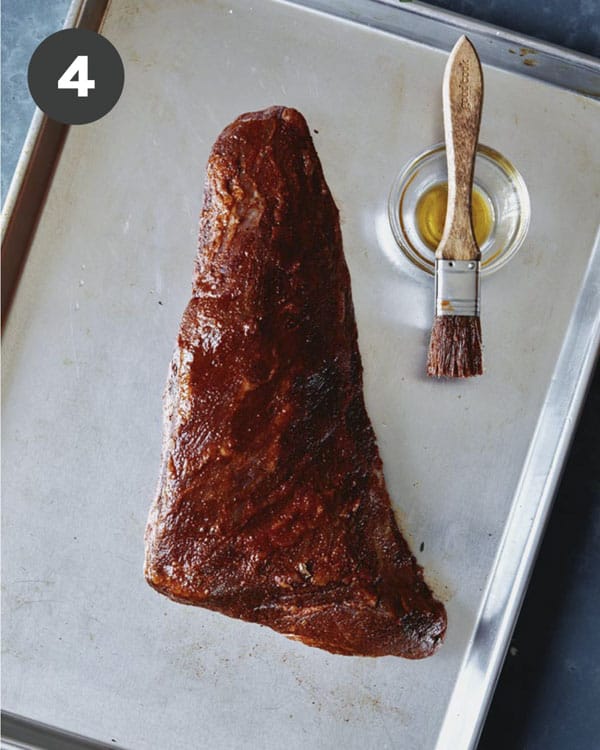 Tri tip with rub being brushed with olive oil.