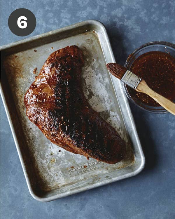 Grilled trip tip being brushed with seasoning. 