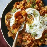 Kimchi fried rice being eaten with a fried egg on top.