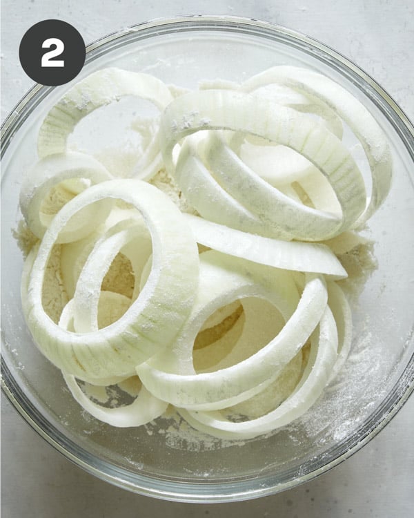 A bowl of onion rings tossed in flour.