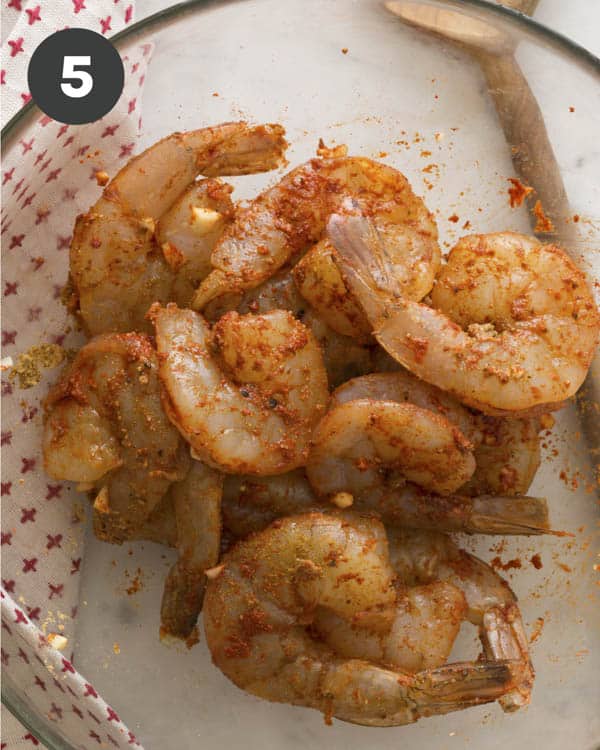 Seasoned shrimp in a glass bowl for shrimp and grits.