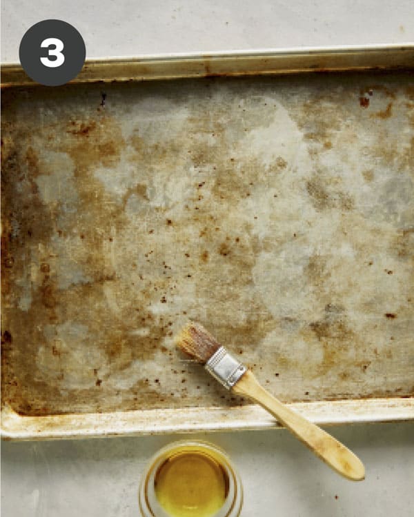 Oiling a baking sheet to toast bruschetta crostini.