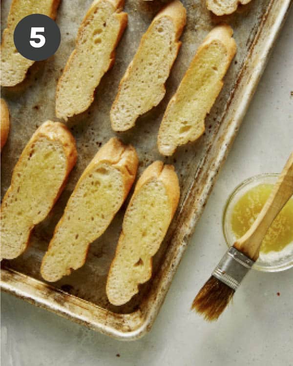 Brushing sliced baguettes with olive oil for bruschetta. 