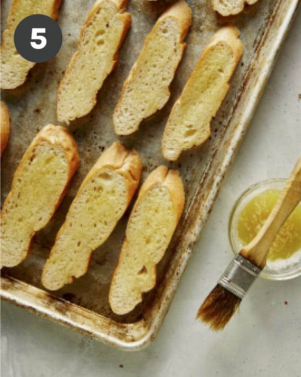 Brushing sliced baguettes with olive oil for bruschetta.