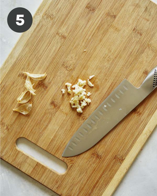 Roasted garlic being minced on a cutting board. 