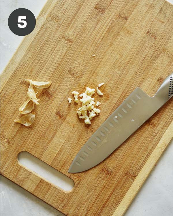 Roasted garlic being minced on a cutting board.
