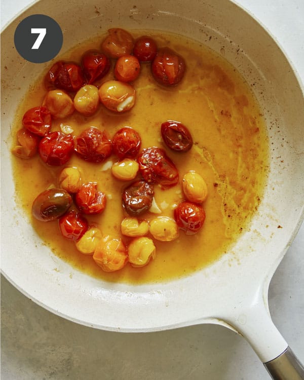 Roasted cherry tomatoes in a skillet to make a pasta dish 