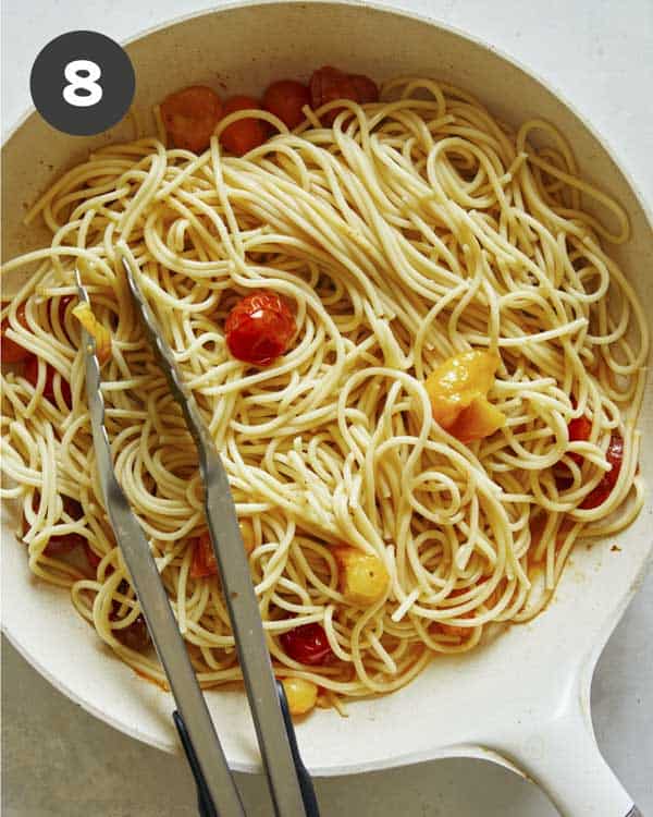 Roasted cherry tomato pasta in a skillet being tossed together. 