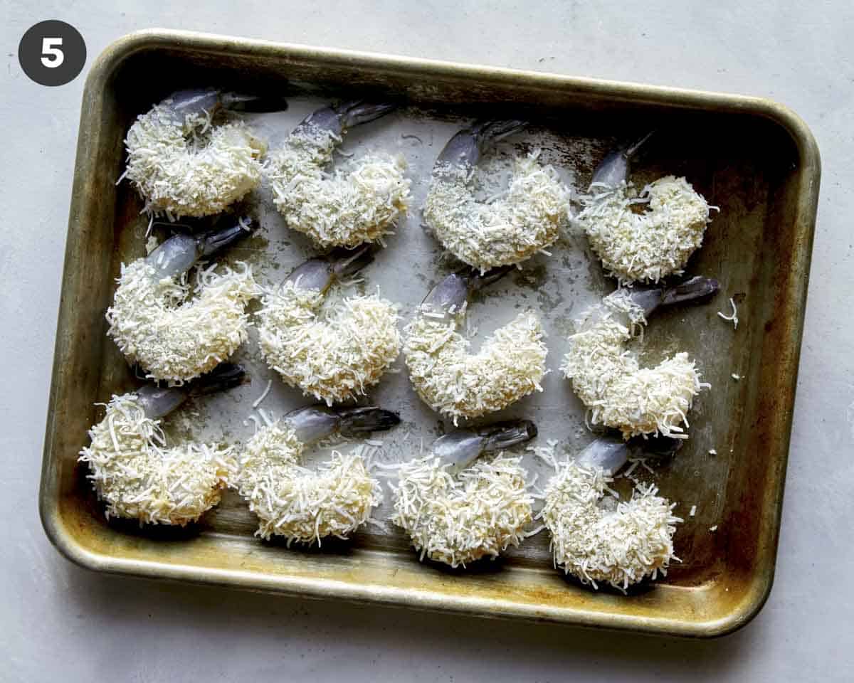 Coconut shrimp on a sheet pan about to go into the refrigerator.