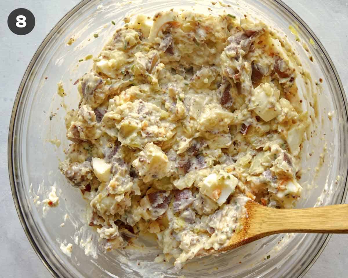 Potato salad in a bowl being mixed.