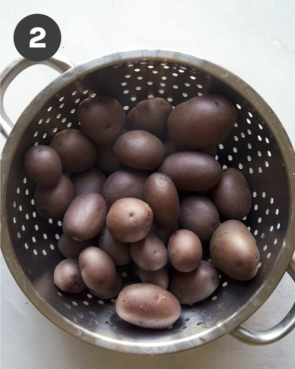 Red potatoes in a colander being drained for creamy potato salad. 