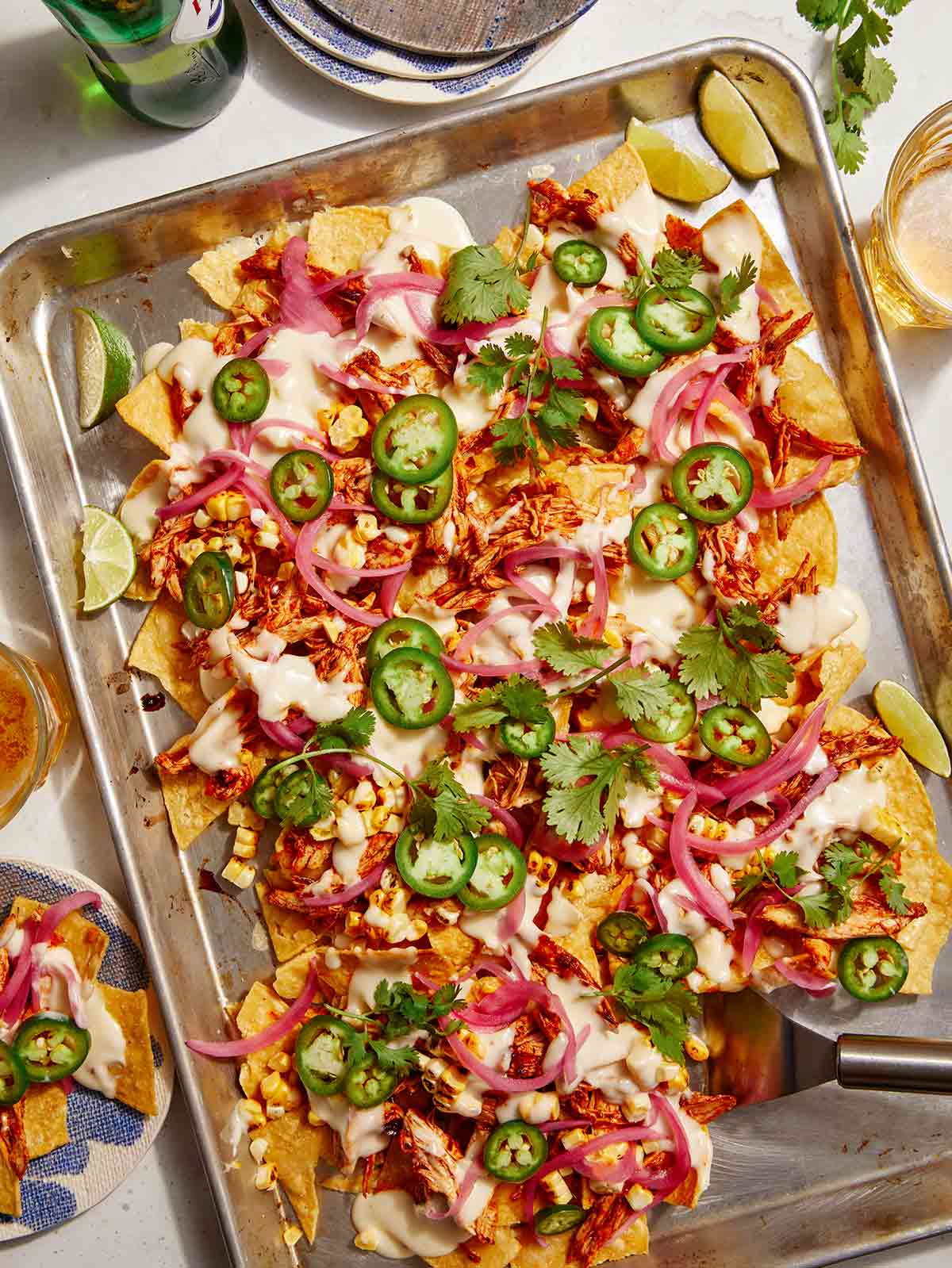 Chipotle chicken sheet pan nachos with plates on the side.