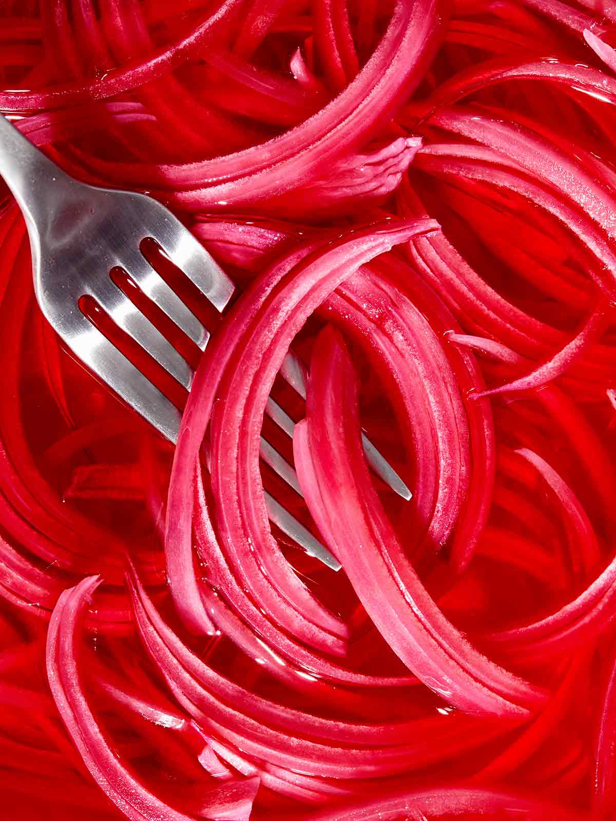 Pickled red onions with a fork in it. 