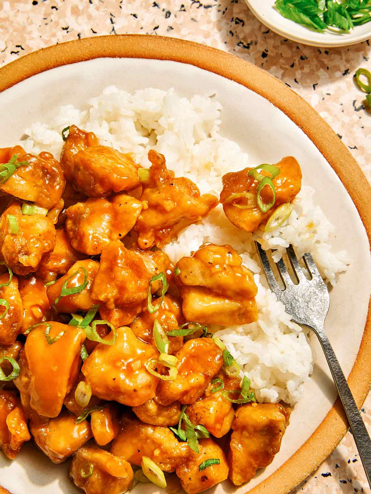 Orange chicken recipe on a plate with rice on the side.