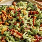 A broccoli salad recipe in a bowl with a spoon.