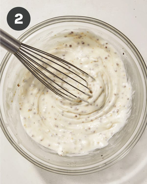 Broccoli salad dressing ingredients mixed in a bowl with a whisk. 