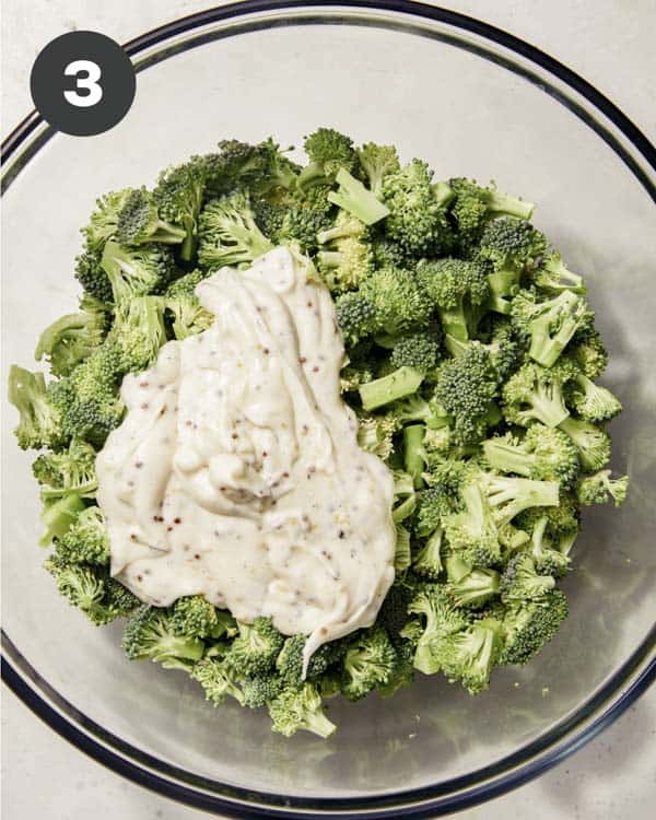 Broccoli in a bowl with dressing to make broccoli salad.