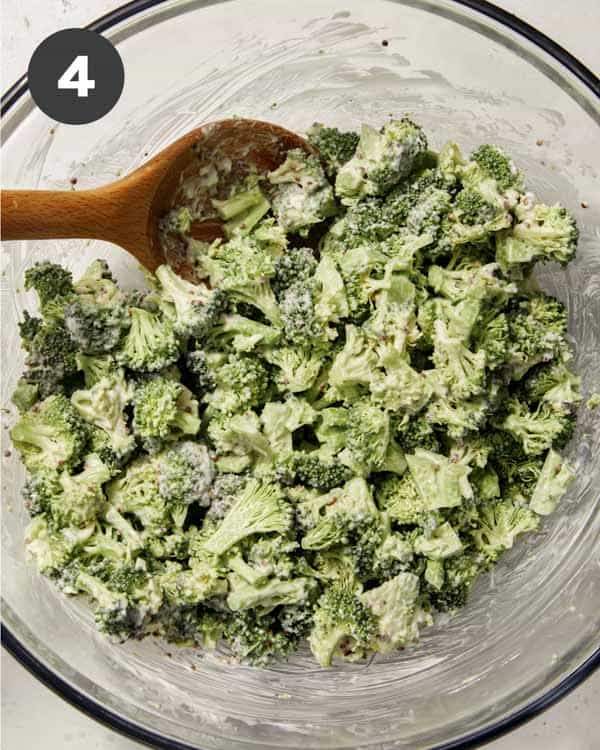 Broccoli salad mixed with dressing in a bowl.