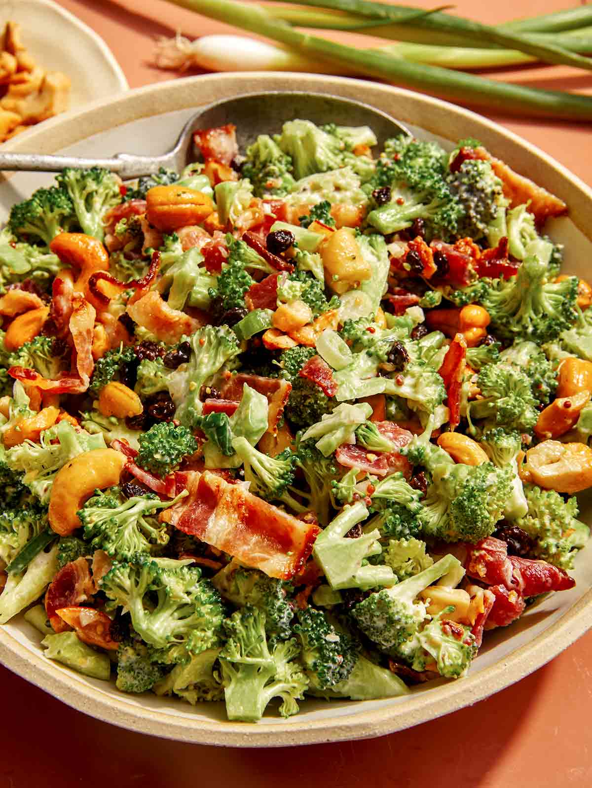 A broccoli salad recipe in a bowl with a spoon. 