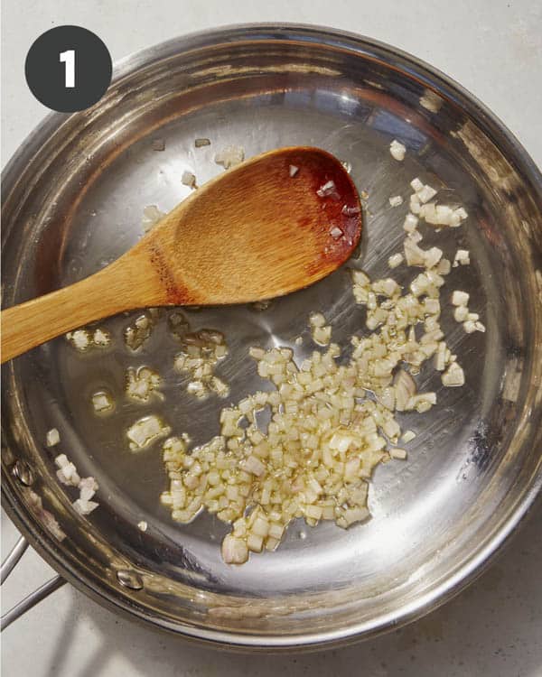Shallots cooking in a skillet with oil.