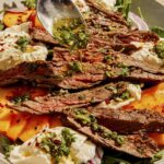 Grilled skirt steak salad with a dressing being poured on top.