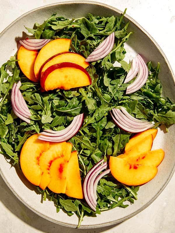 A peach and red onion salad with lettuce. 