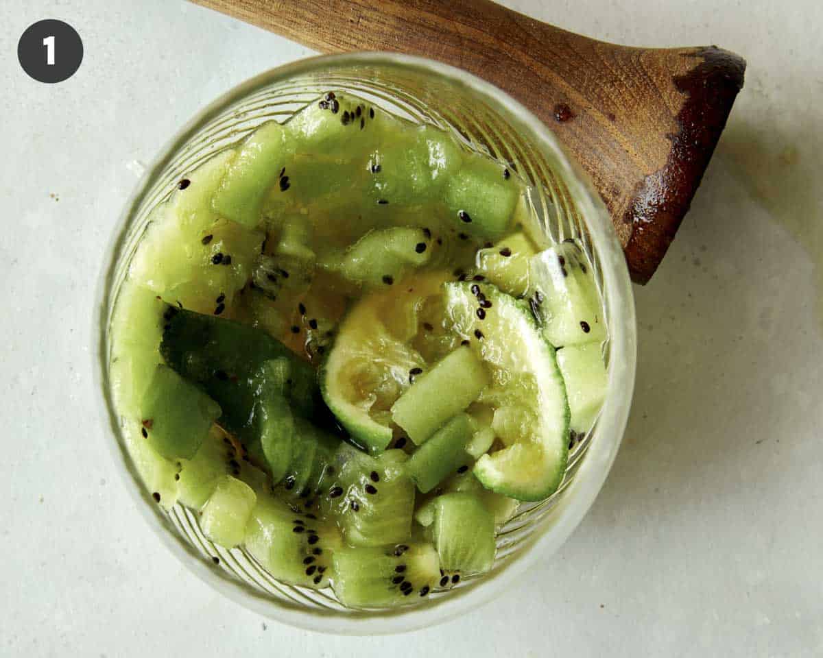 Muddled kiwis and limes in a drink glass. 