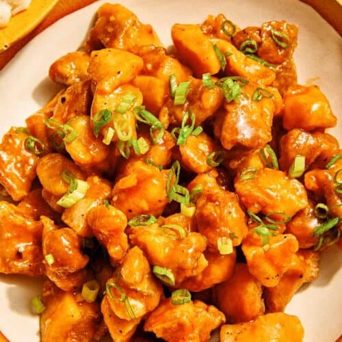 Orange chicken recipe in a bowl with rice on the side.