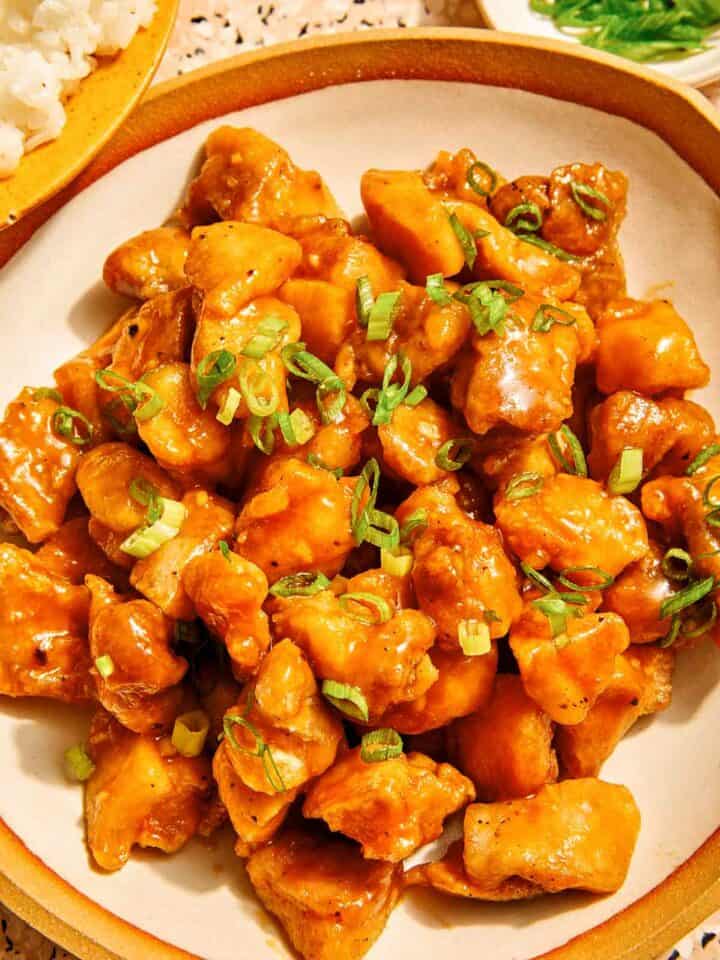 Orange chicken recipe in a bowl with rice on the side.