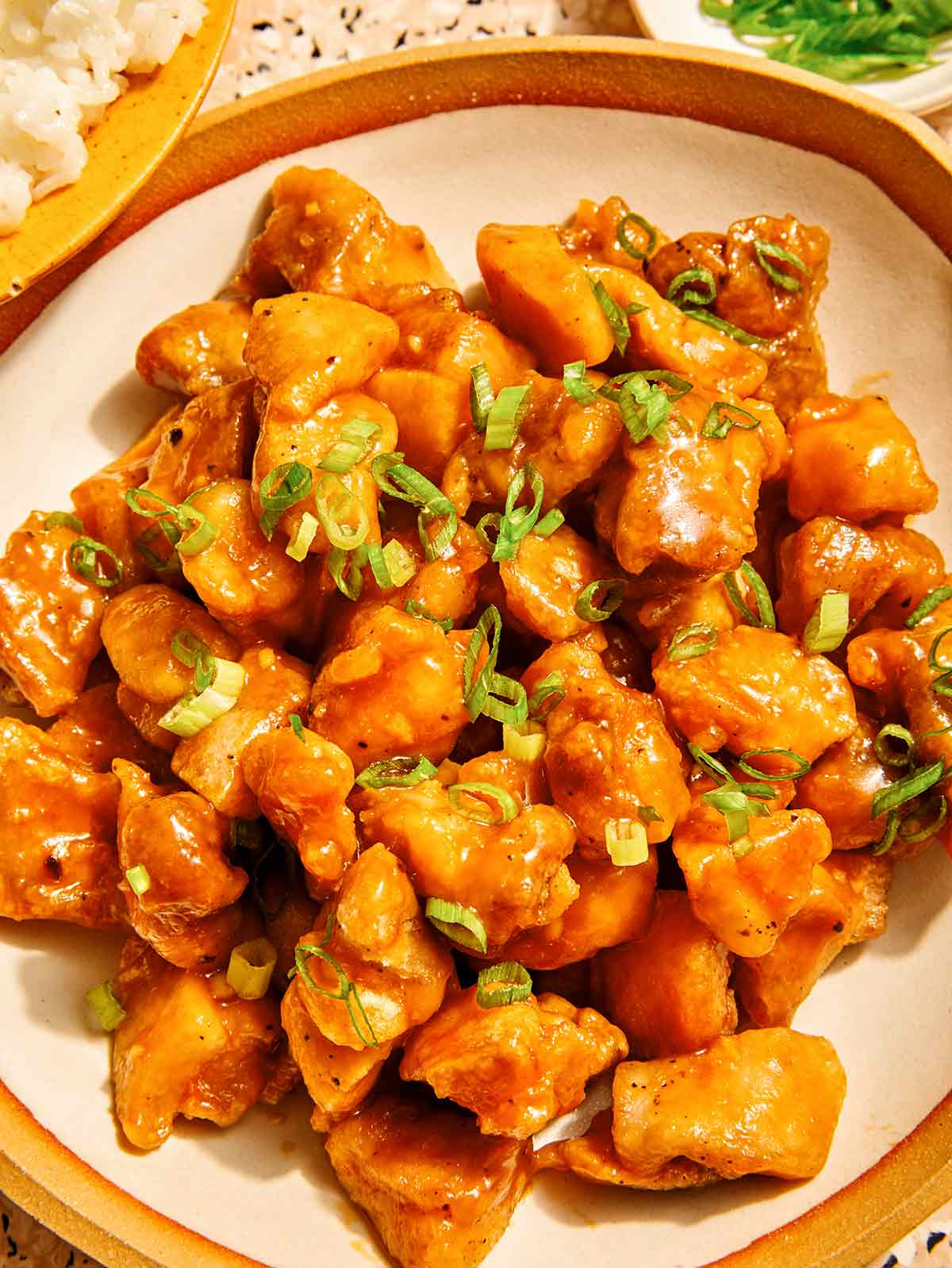 Orange chicken recipe in a bowl with rice on the side.