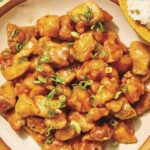 Orange chicken recipe in a bowl with rice on the side.