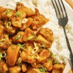 Orange chicken recipe on a plate with rice on the side.