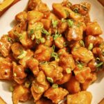 Orange chicken recipe in a bowl with rice on the side.