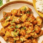 Orange chicken in a bowl with rice on the side.