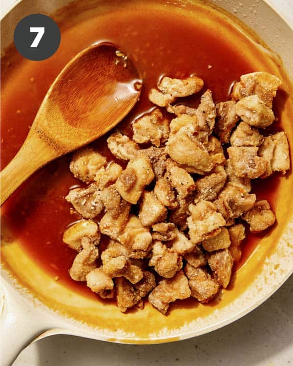 Orange sauce with fried chicken in a saucepan.