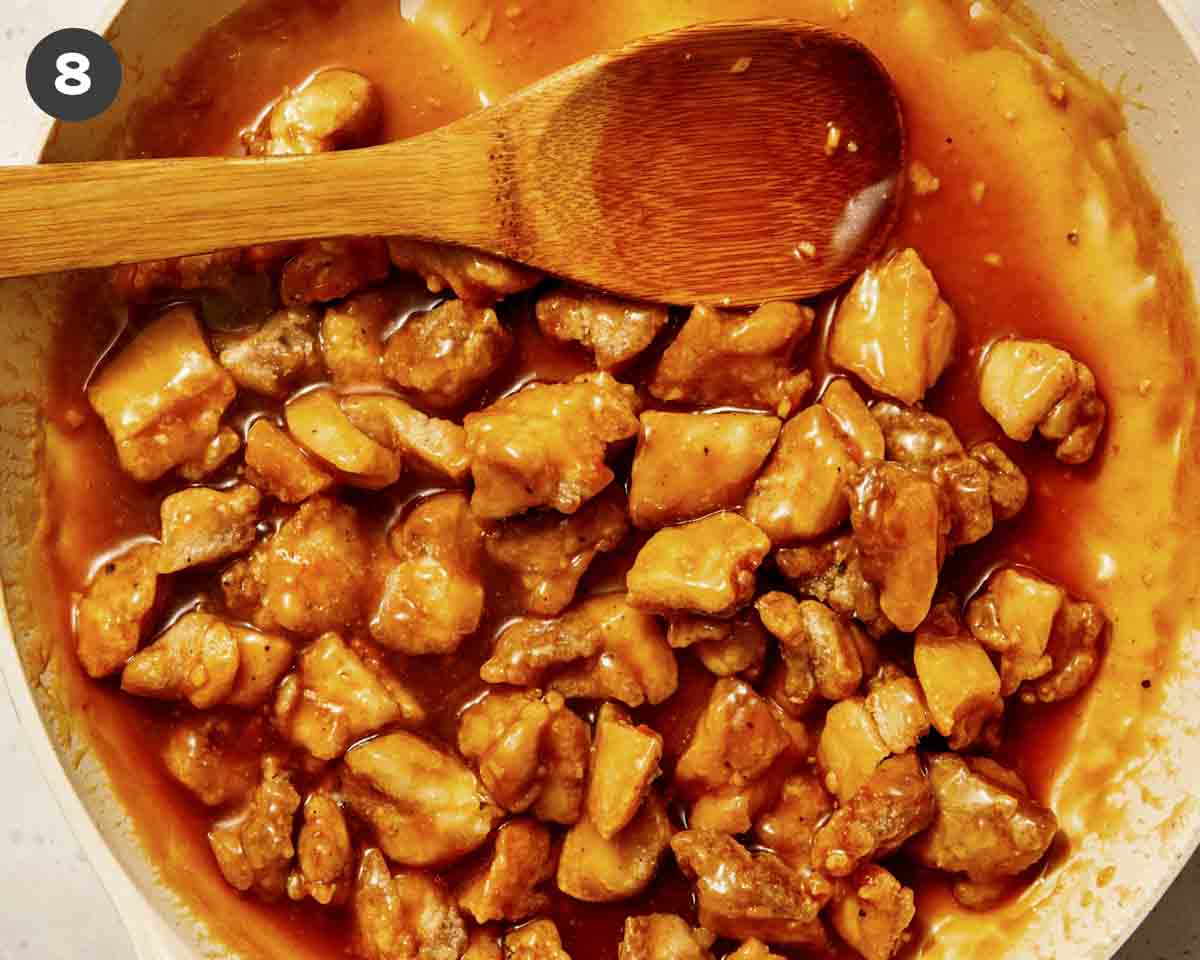 Orange chicken tossed in a saucepan.