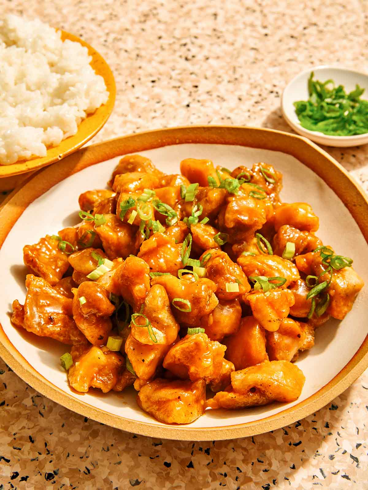 Orange chicken in a bowl with rice on the side.