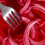 Pickled red onions with a fork in it.