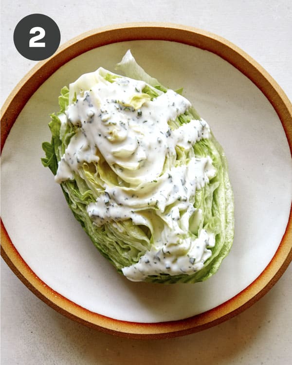 A wedge of lettuce covered in buttermilk ranch.