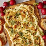 Butter board with bread and radishes on the side.