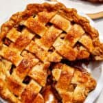 A slice of apple pie on a plate with a fork next to it.